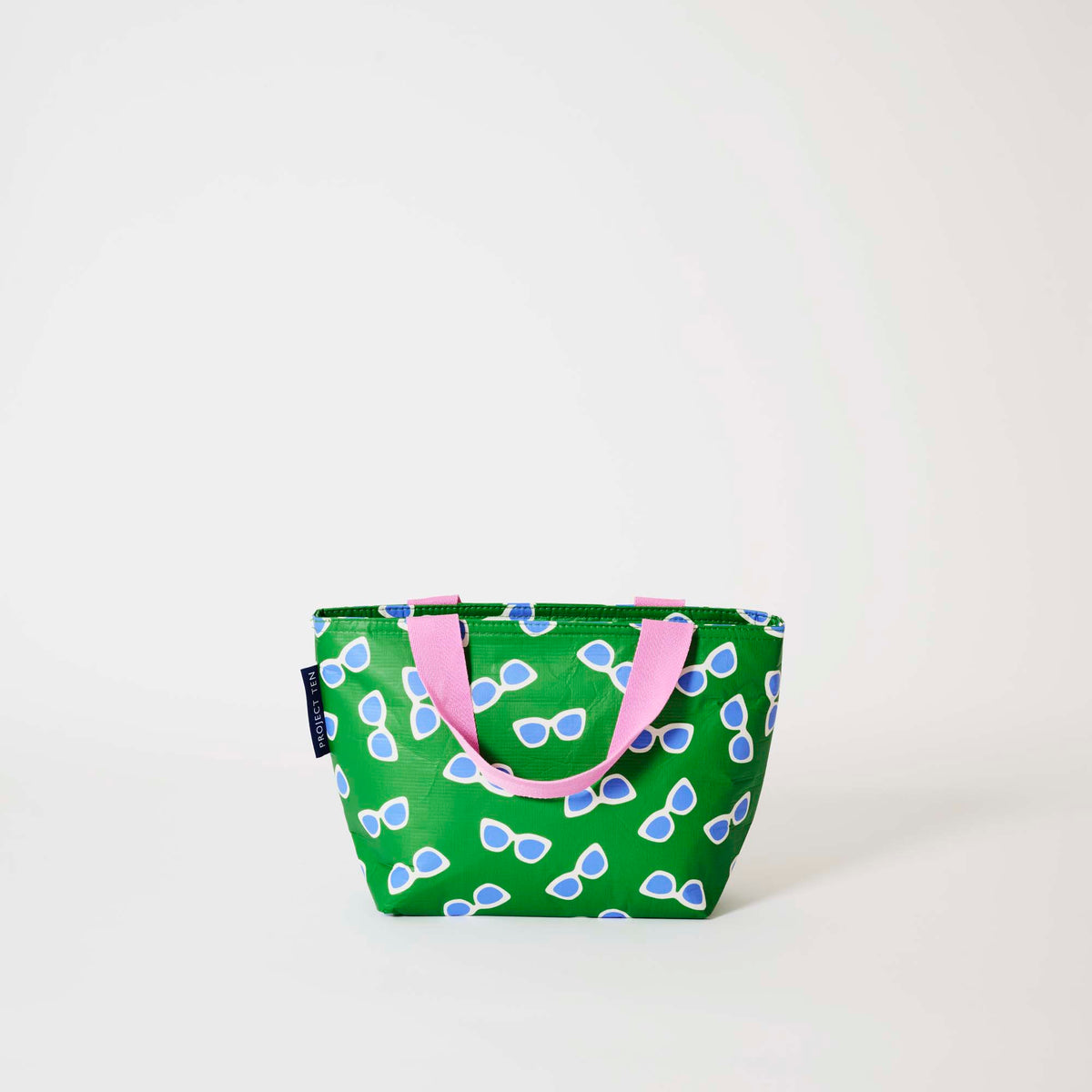 Our Sunglasses Mini Tote, a compact tote bag in green with a scattered print of blue-lensed, white-framed sunglasses and two pink carry handles.