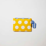 Our Yellow Polka Dot Mini Zip Pouch, a small rectangular pouch in bright yellow with ecru polka dots and a blue zip and blue and ecru striped handle.