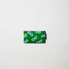 Our Sunglasses Tiny Zip Pouch, a small flat pouch in green with a scattered print of ecru framed sunglasses with blue lenses, and a pink zip.