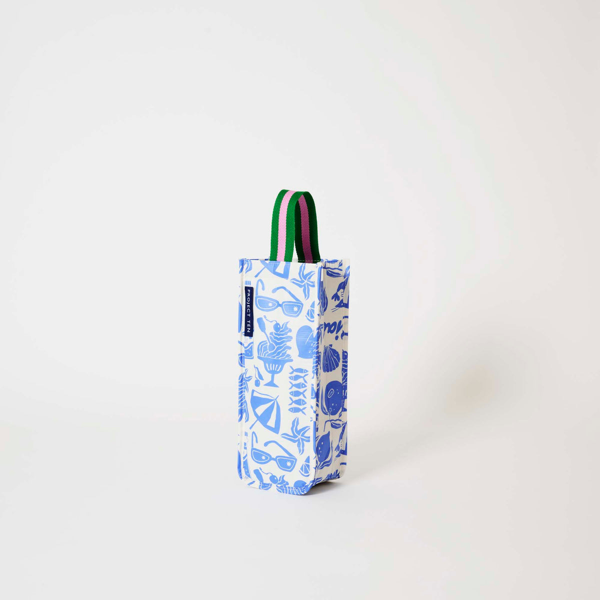 Our Feast Wine Bag, a tall narrow bottle bag in an ecru base with a blue seaside print of sunglasses, ice cream sundaes, beach umbrellas, starfish and sardines, with a single green and pink striped carry handle.
