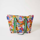 Our Coastal Floral Zip Medium Tote covered in bright retro daisies in orange, pink, yellow and blue on a navy background, with a full zip closure across the top and long green and pink striped shoulder straps.