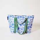 Our Feast Zip Medium Tote in a blue and ecru print of shells, gelato, soda bottles, sunglasses, beach umbrellas and the word "Ciao", with a full zip closure across the top and long green and pink striped shoulder straps.